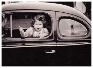 A young child sitting in the back of an old car.